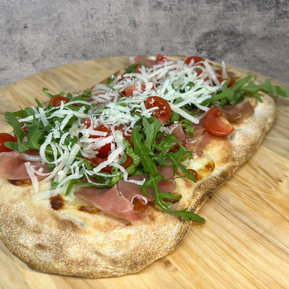 Pinsa con mozzarella, prosciutto crudo di Parma, pomodorini, rucola e scaglie di parmigiano